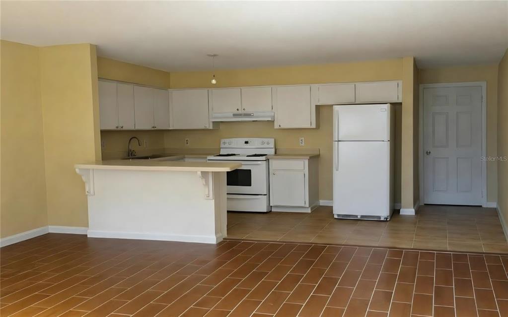 A kitchen with white cabinets, white appliances, and a breakfast bar over tiled floors — 1709 E IDELL STREET UNIT B, TAMPA, FL