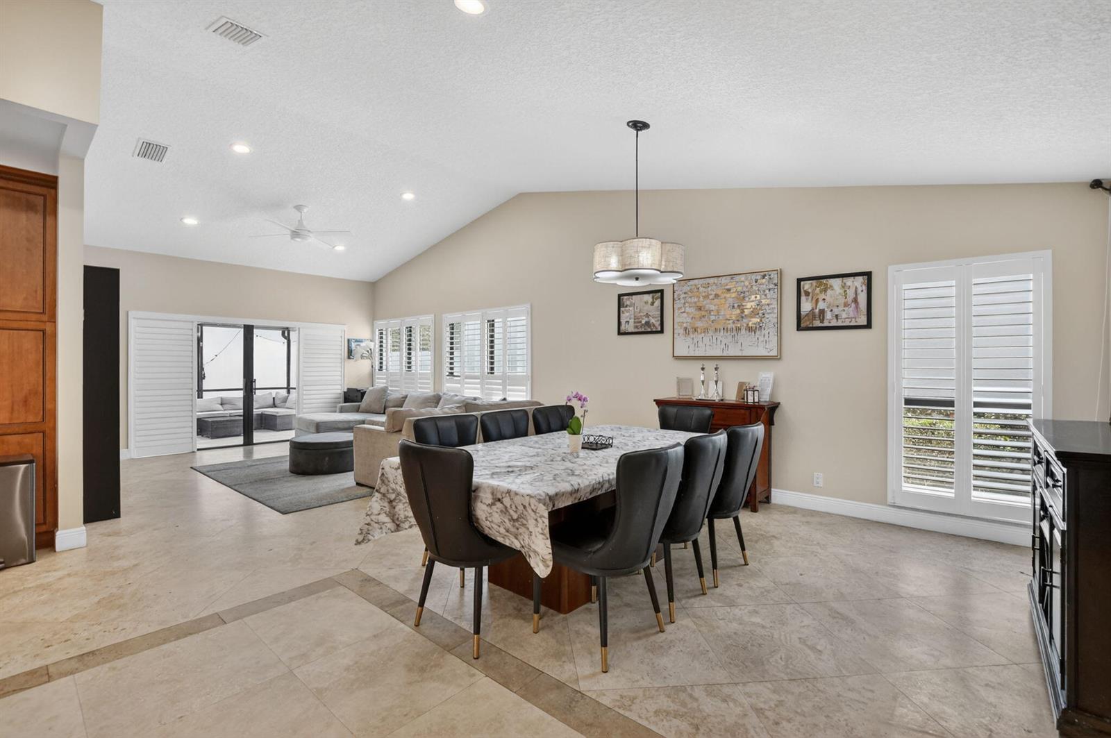 A dining area with a marble-topped table and black chairs sits before a living room — 6790 Jardin Place, Boca Raton FL 33433, BOCA RATON, FL