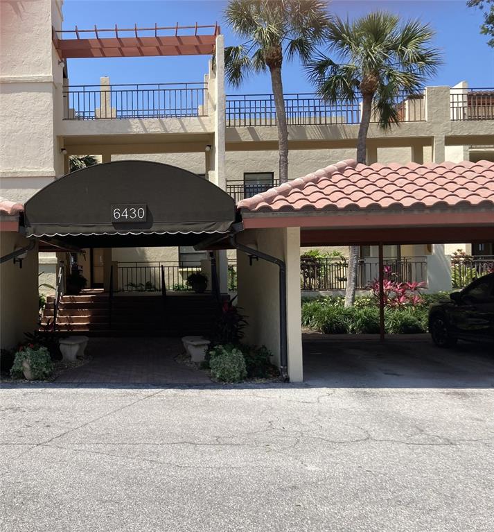 The exterior of a multi-story building features a covered entrance with a black awning — 6430 SUN EAGLE LANE UNIT 203, BRADENTON, FL