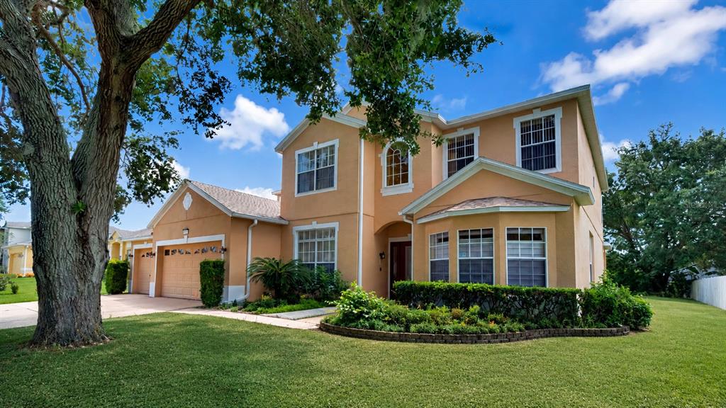 A two-story peach-colored house with a garage and a large tree in the front yard — 3295 SAFE HARBOR LANE, LAKE MARY, FL