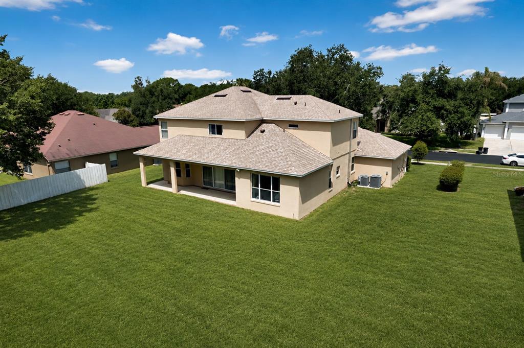 An aerial view of the back of a two-story tan house with a large lawn — 3295 SAFE HARBOR LANE, LAKE MARY, FL
