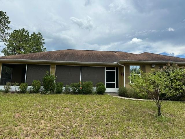 The exterior of a single-story house features a screened-in porch and a brown shingled roof — 2551 SW HARBOR HILLS ROAD, DUNNELLON, FL