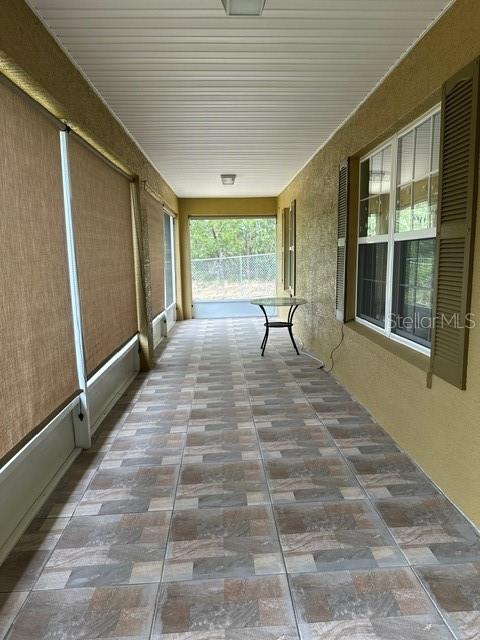 A covered patio features tiled flooring, screen walls, and a small metal table — 2551 SW HARBOR HILLS ROAD, DUNNELLON, FL