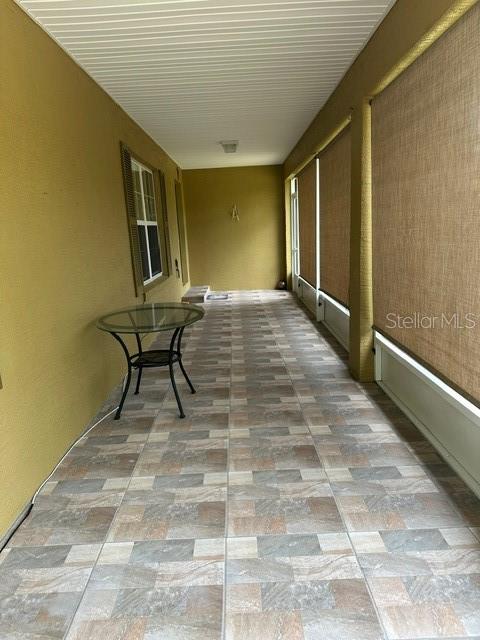 A covered patio features tiled flooring, a glass-topped table, and roll-down privacy shades — 2551 SW HARBOR HILLS ROAD, DUNNELLON, FL