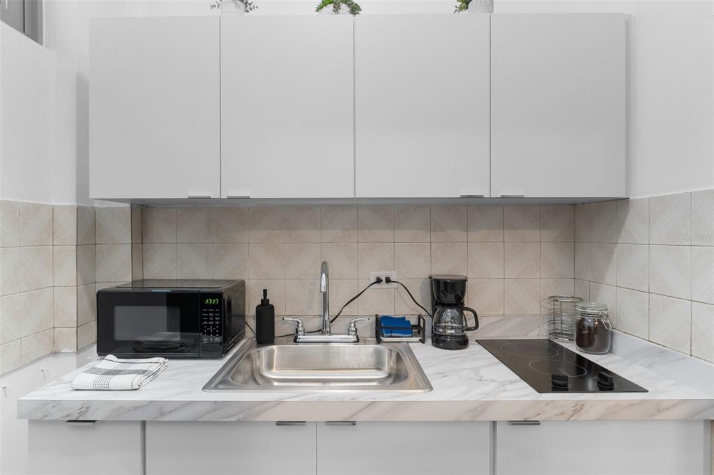 A small kitchen features white cabinets, a stainless steel sink, and a marble-patterned countertop — 261 DUFFAUNT, SAN JUAN, PR
