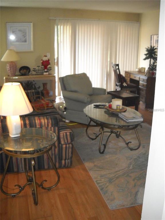 A living room features a striped sofa, a glass coffee table, and a desk area — 3471 CLARK ROAD UNIT 269, SARASOTA, FL
