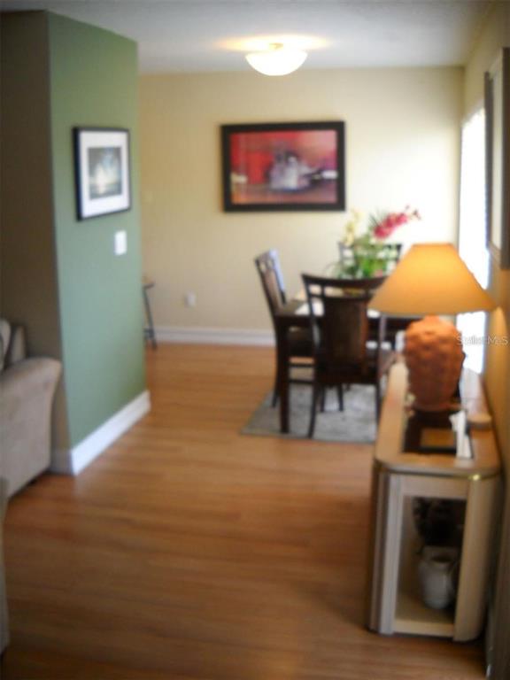 A dining area with wood flooring, a table with chairs, and a console table — 3471 CLARK ROAD UNIT 269, SARASOTA, FL