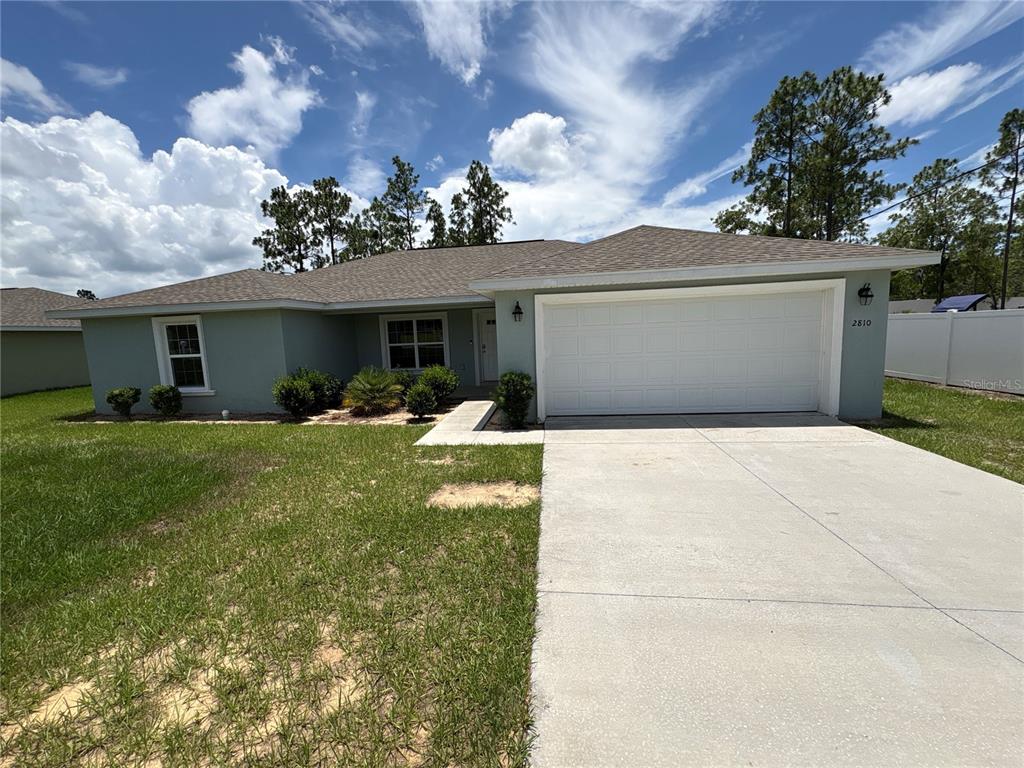 A single-story house with a light green exterior, a two-car garage, and a concrete driveway — 2810 W PINTADO DRIVE, DUNNELLON, FL