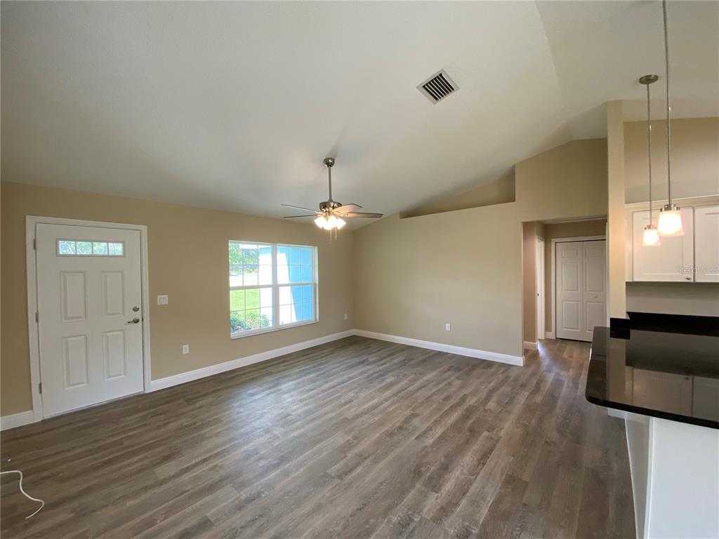 An open-concept living room features vaulted ceilings, wood-look flooring, and a ceiling fan — 2810 W PINTADO DRIVE, DUNNELLON, FL
