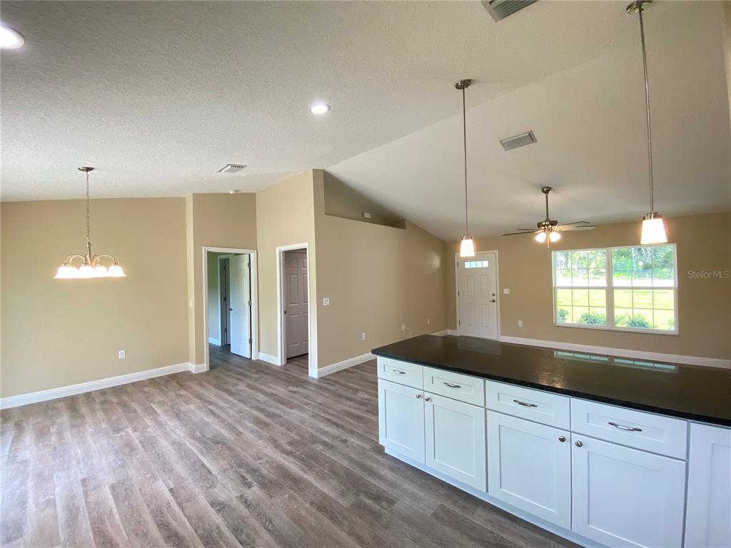 A kitchen island with dark countertops and white cabinets faces an open living area — 2810 W PINTADO DRIVE, DUNNELLON, FL