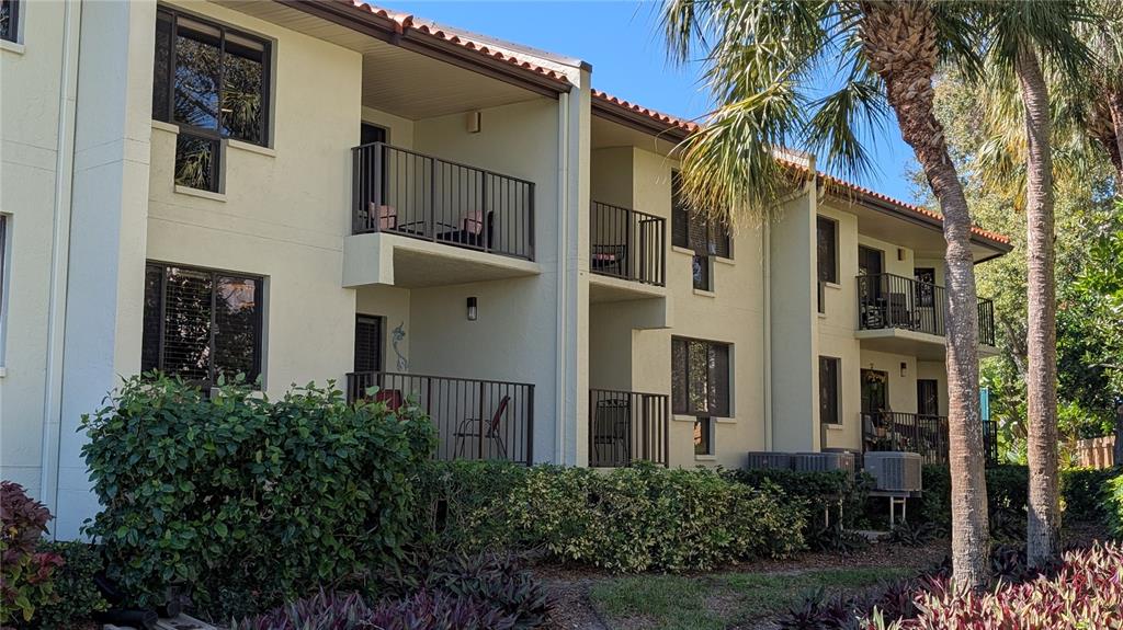 The exterior of a multi-story apartment building features balconies and lush landscaping — 1515 PINELLAS BAYWAY S UNIT 46, ST PETERSBURG, FL