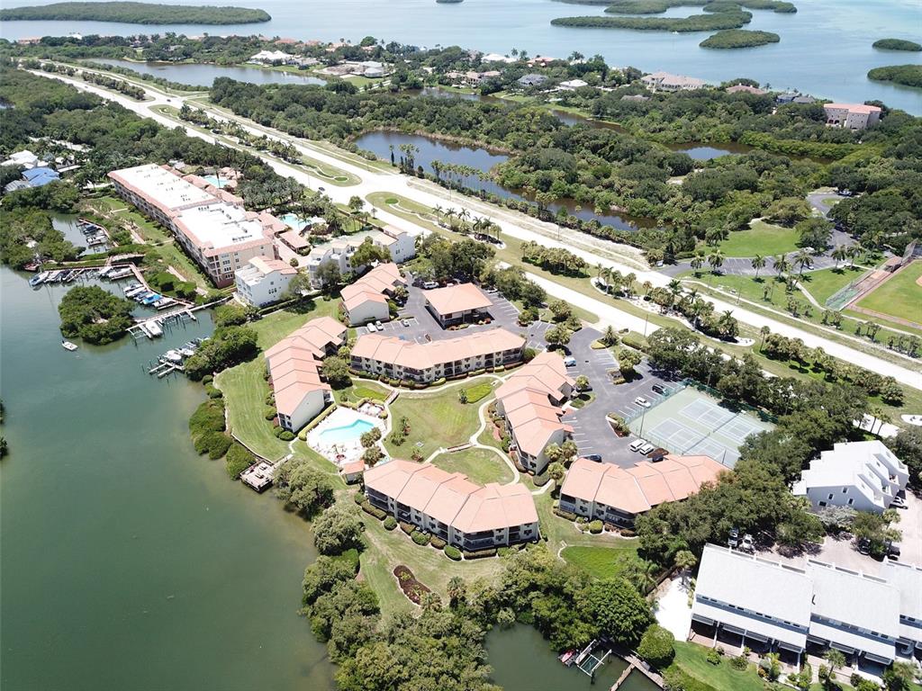 An aerial view shows a waterfront condominium complex with a pool and tennis courts — 1515 PINELLAS BAYWAY S UNIT 46, ST PETERSBURG, FL