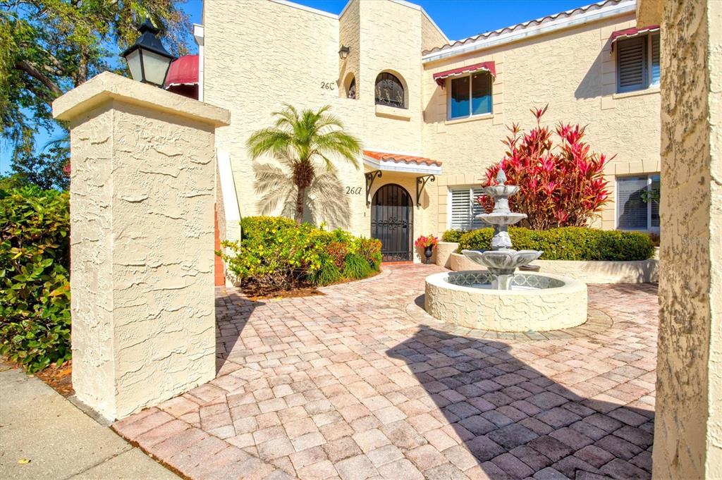 A stone-paved courtyard features a tiered fountain in front of a stucco building entrance — 6101 34TH STREET W UNIT 26C, BRADENTON, FL