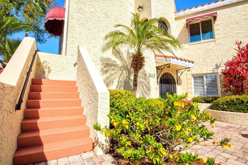 An exterior view of a stucco building with a staircase, palm tree, and landscaping — 6101 34TH STREET W UNIT 26C, BRADENTON, FL
