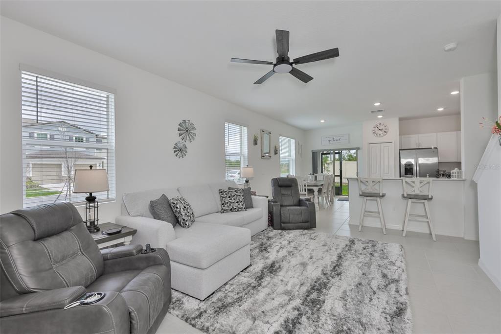 An open-concept living room and kitchen featuring a grey sectional, recliner, and breakfast bar — 2661 SUNRAY VENUS WAY, RUSKIN, FL