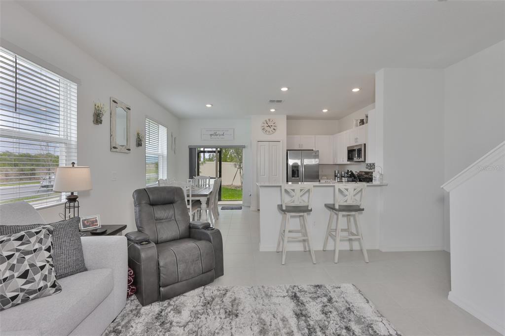 A living room and kitchen area with white walls, tile floors, and a gray recliner — 2661 SUNRAY VENUS WAY, RUSKIN, FL
