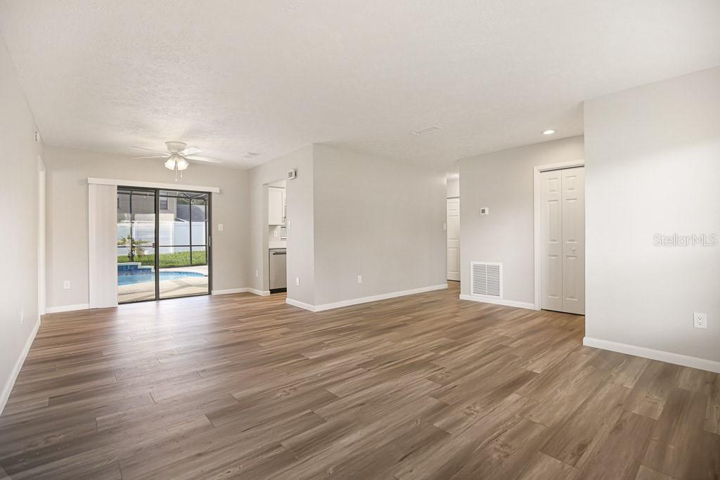 An empty living room with wood-look flooring, a ceiling fan, and a sliding glass door — 423 VAN REED MANOR DRIVE, BRANDON, FL