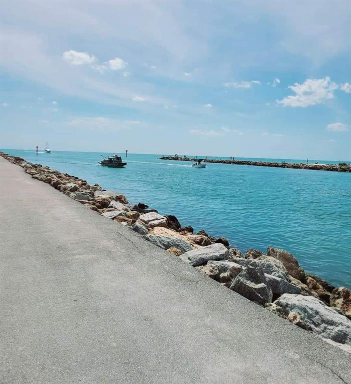 A paved walkway runs alongside a rocky jetty bordering a channel with boats — 14165 DANIELS AVENUE, PORT CHARLOTTE, FL