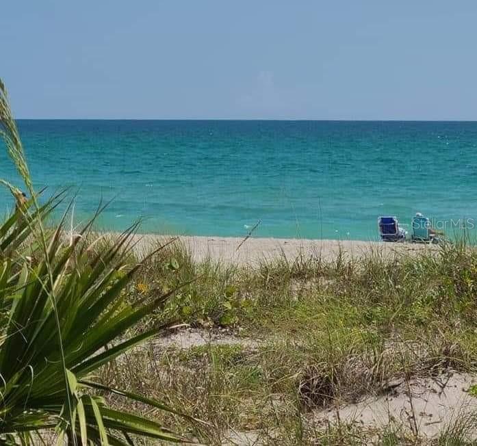 A view of a sandy beach and turquoise ocean from behind coastal dune vegetation — 14165 DANIELS AVENUE, PORT CHARLOTTE, FL