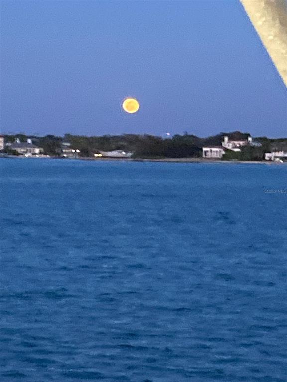 A full moon hangs over a body of water with a distant shoreline and buildings — 14165 DANIELS AVENUE, PORT CHARLOTTE, FL