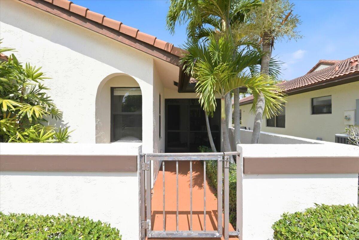 A gated entrance leads to a covered patio area with a palm tree and house — 21583 Villa Nova Drive, Boca Raton FL 33433, BOCA RATON, FL