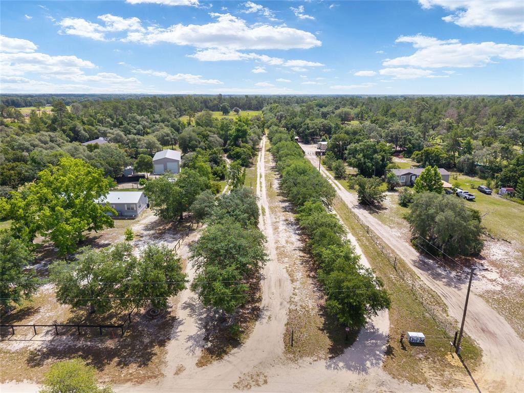 An aerial view shows a dirt driveway lined with trees leading toward rural properties — 17171 SW 17TH CIRCLE, OCALA, FL