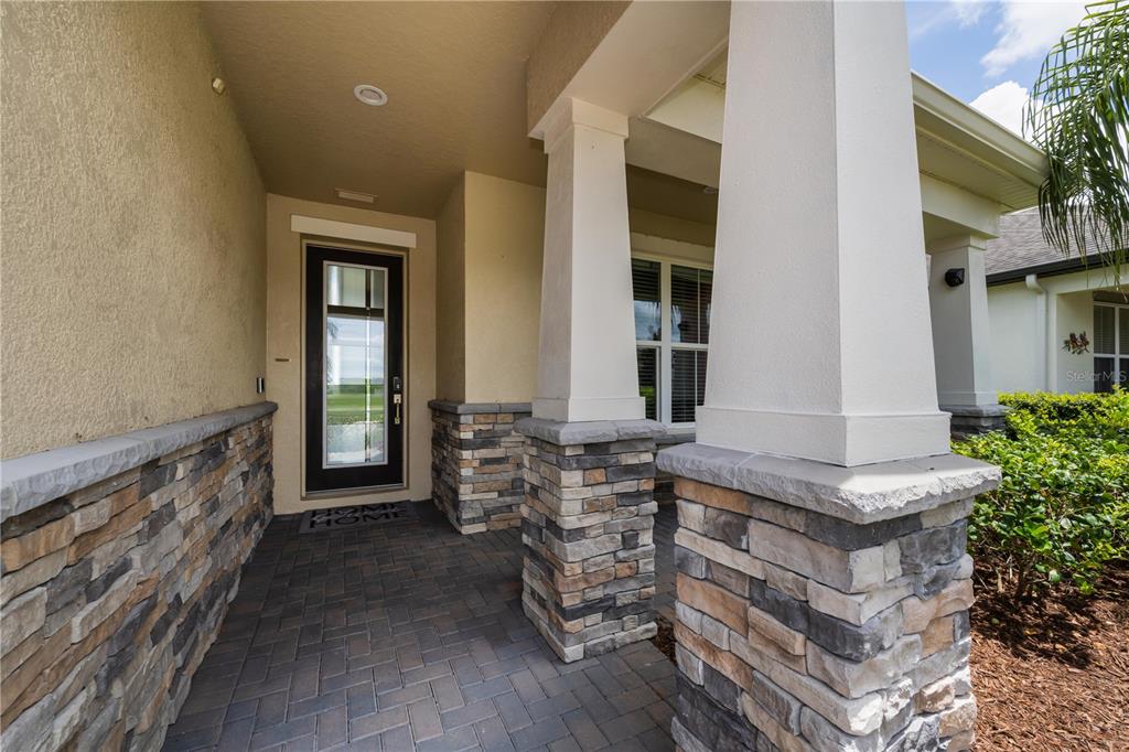 A single-story house with a two-car garage, stone accents, and a landscaped front yard — 18233 ROSEATE DRIVE, LUTZ, FL