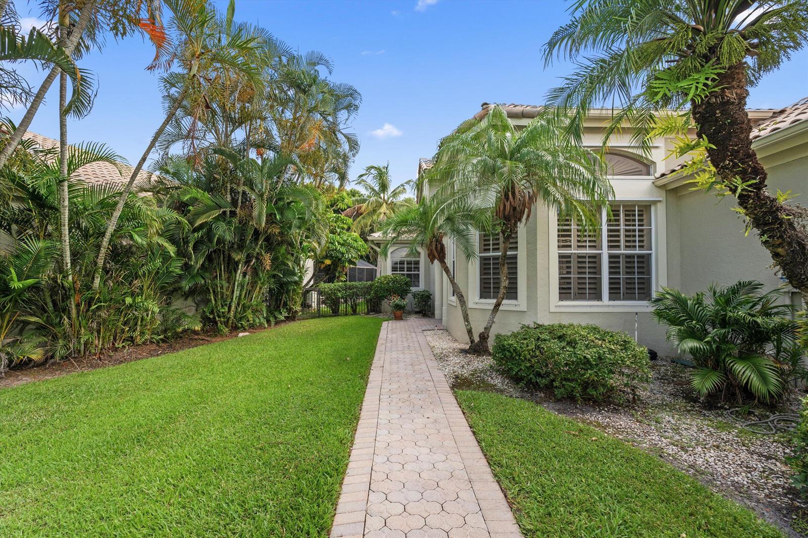 A paved walkway leads past a house with palm trees and a green lawn — 12557 Mallet Circle, Wellington FL 33414, WELLINGTON, FL
