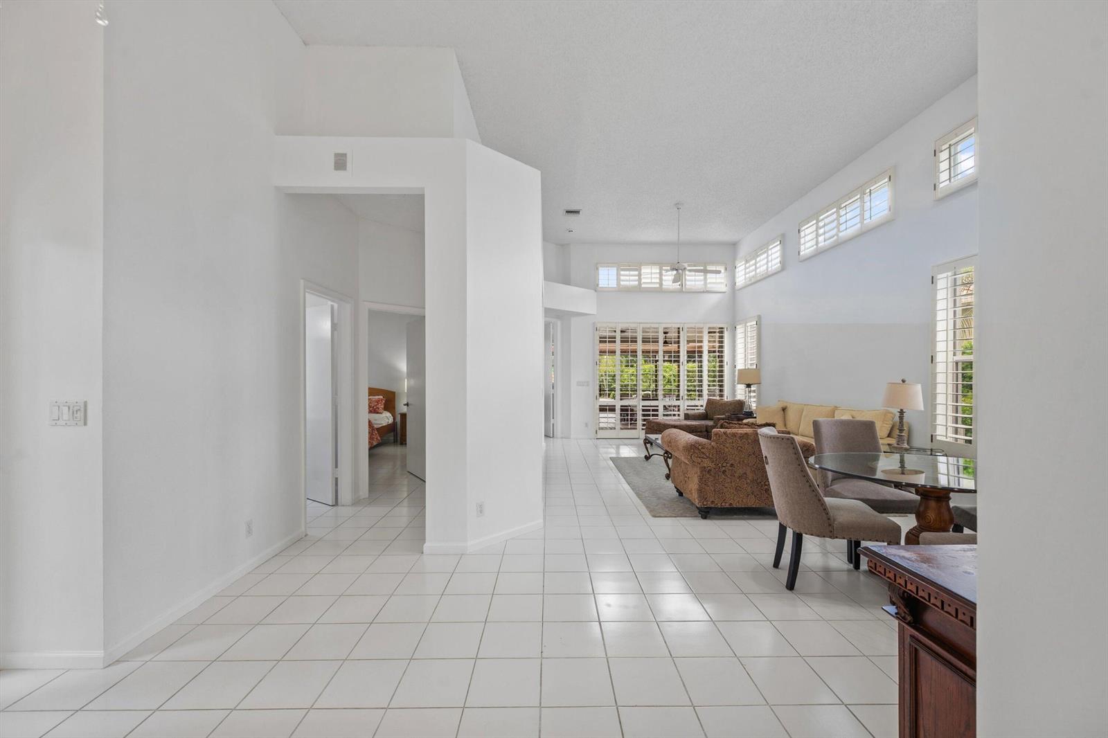 A bright living and dining area features white tile floors, high ceilings, and large windows — 12557 Mallet Circle, Wellington FL 33414, WELLINGTON, FL