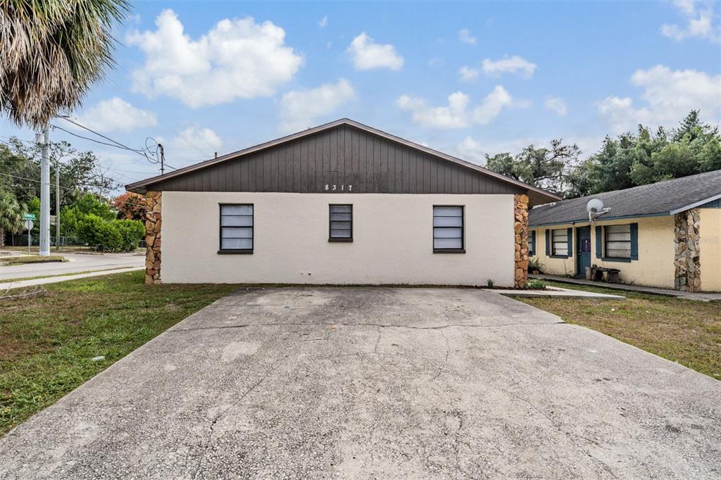 A single-story house with a concrete driveway, stucco walls, and a brown gabled roof — 8317 N MARKS STREET, TAMPA, FL