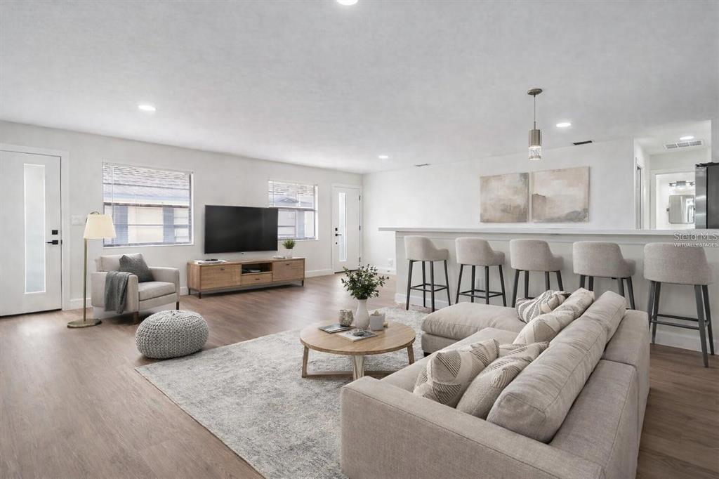 This living room features light wood flooring, a sectional sofa, and a kitchen breakfast bar — 8317 N MARKS STREET, TAMPA, FL