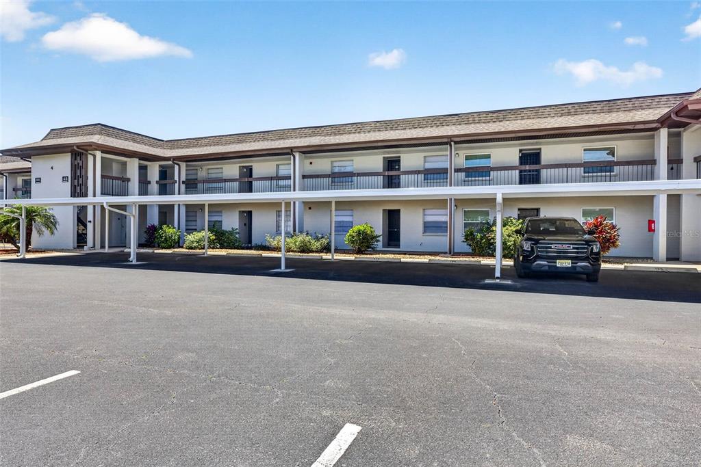 A two-story apartment building features a covered parking area and a second-floor balcony — 5197 SILENT LOOP UNIT 124, NEW PORT RICHEY, FL