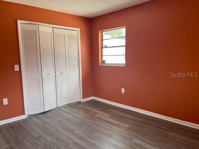 A bedroom with orange walls, wood-look flooring, and white louvered closet doors — 1717 STATE ROAD 17 N, SEBRING, FL