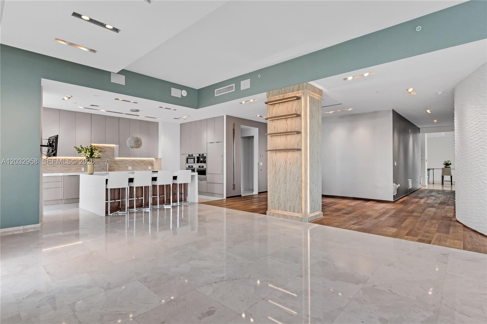 A modern open-concept kitchen features a marble island, light cabinetry, and polished tile flooring — 900 Brickell Key Blvd # 1002, Miami FL 33131, MIAMI, FL