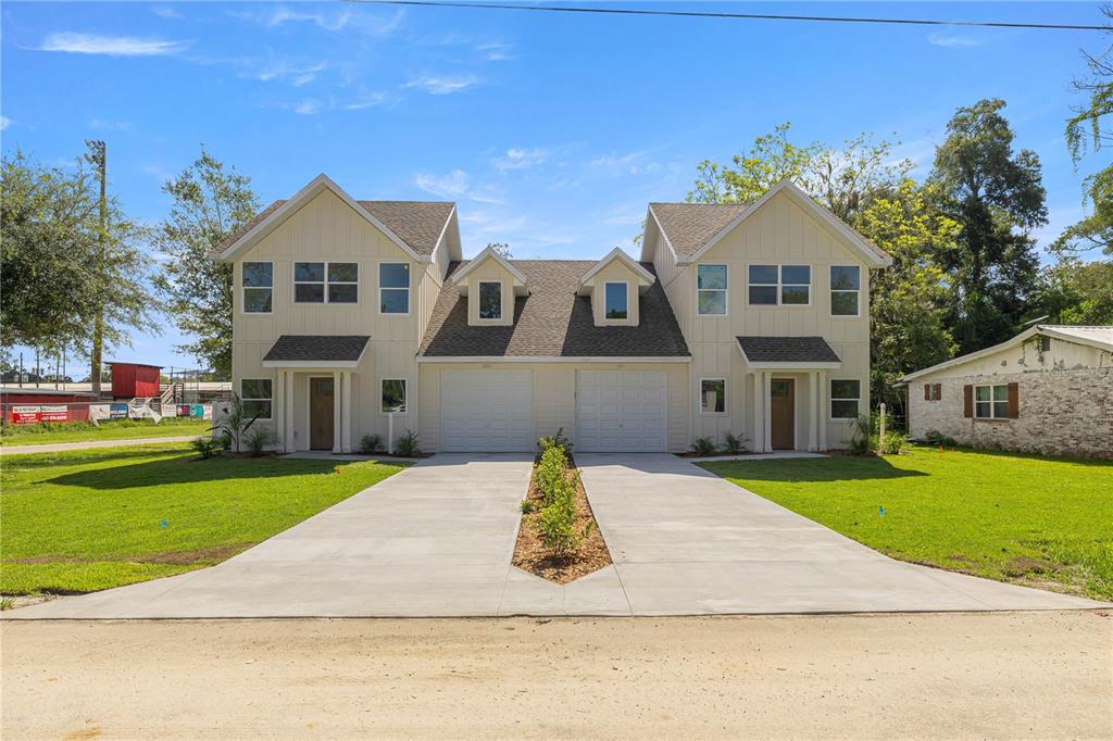 A two-story duplex with light siding, two garage doors, and a shared concrete driveway — 305 SE 5TH TERRACE, WILLISTON, FL