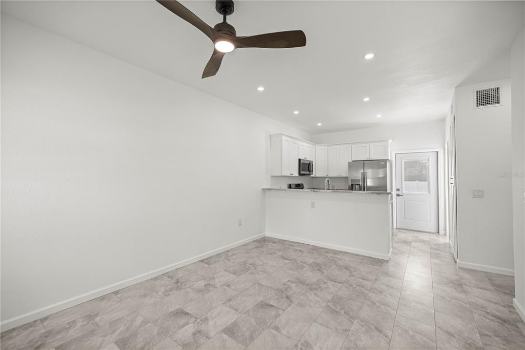A kitchen with white cabinets and stainless steel appliances overlooks a tiled dining area — 305 SE 5TH TERRACE, WILLISTON, FL