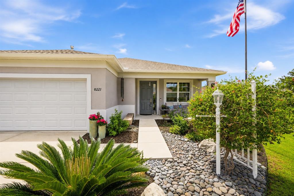 A single-story house exterior features a garage, a front entrance, and a landscaped rock garden — 8221 SW 78TH TERRACE ROAD, OCALA, FL