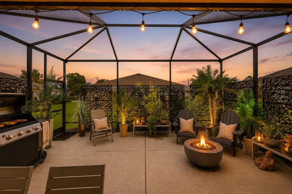 A screened-in patio features a fire pit, outdoor seating, a grill, and decorative privacy screens — 8221 SW 78TH TERRACE ROAD, OCALA, FL