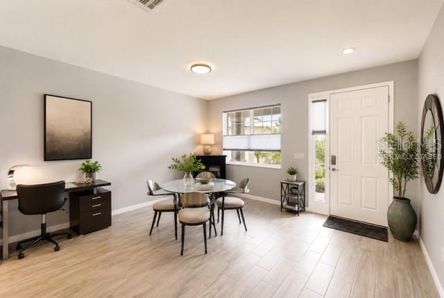A dining area and home office space feature light wood flooring and a white door — 8221 SW 78TH TERRACE ROAD, OCALA, FL
