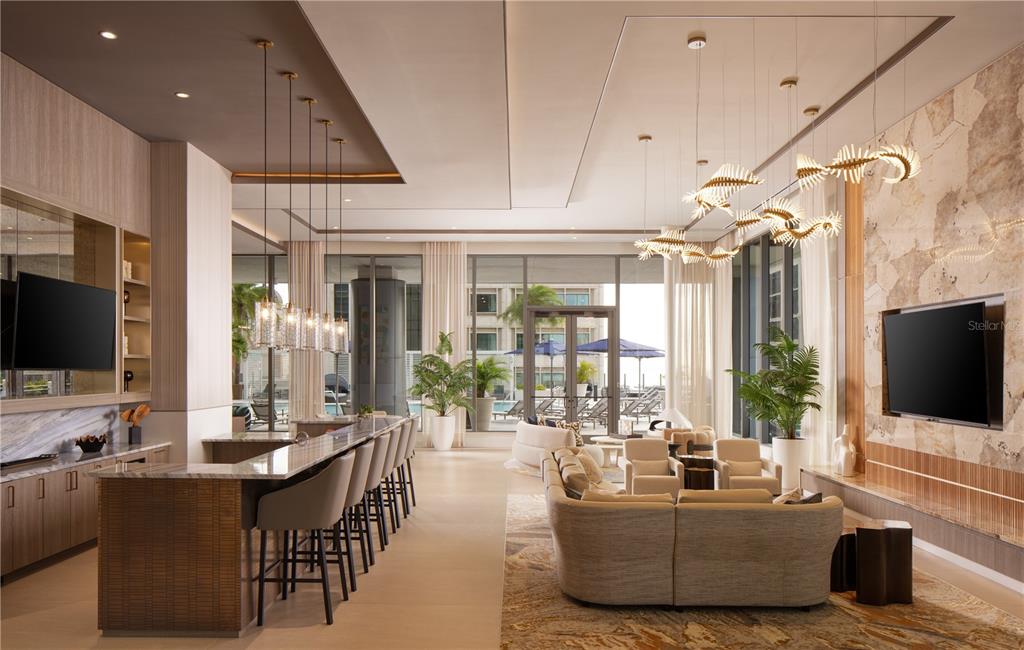 A modern lounge area features a bar, a seating area with a sofa, and large windows — 275 1ST AVENUE S UNIT 3406, ST PETERSBURG, FL