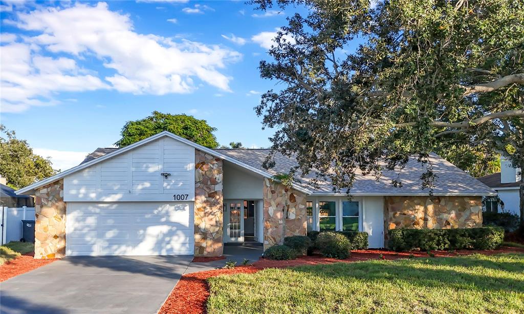 A single-story house with a stone facade, white siding, and a paved driveway — 1007 NW 82ND STREET, BRADENTON, FL
