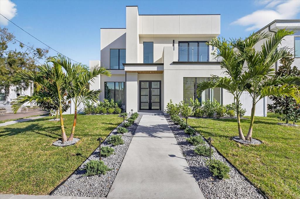 A modern two-story house with a concrete walkway, palm trees, and a gravel border — 3702 S LYNWOOD AVENUE, TAMPA, FL