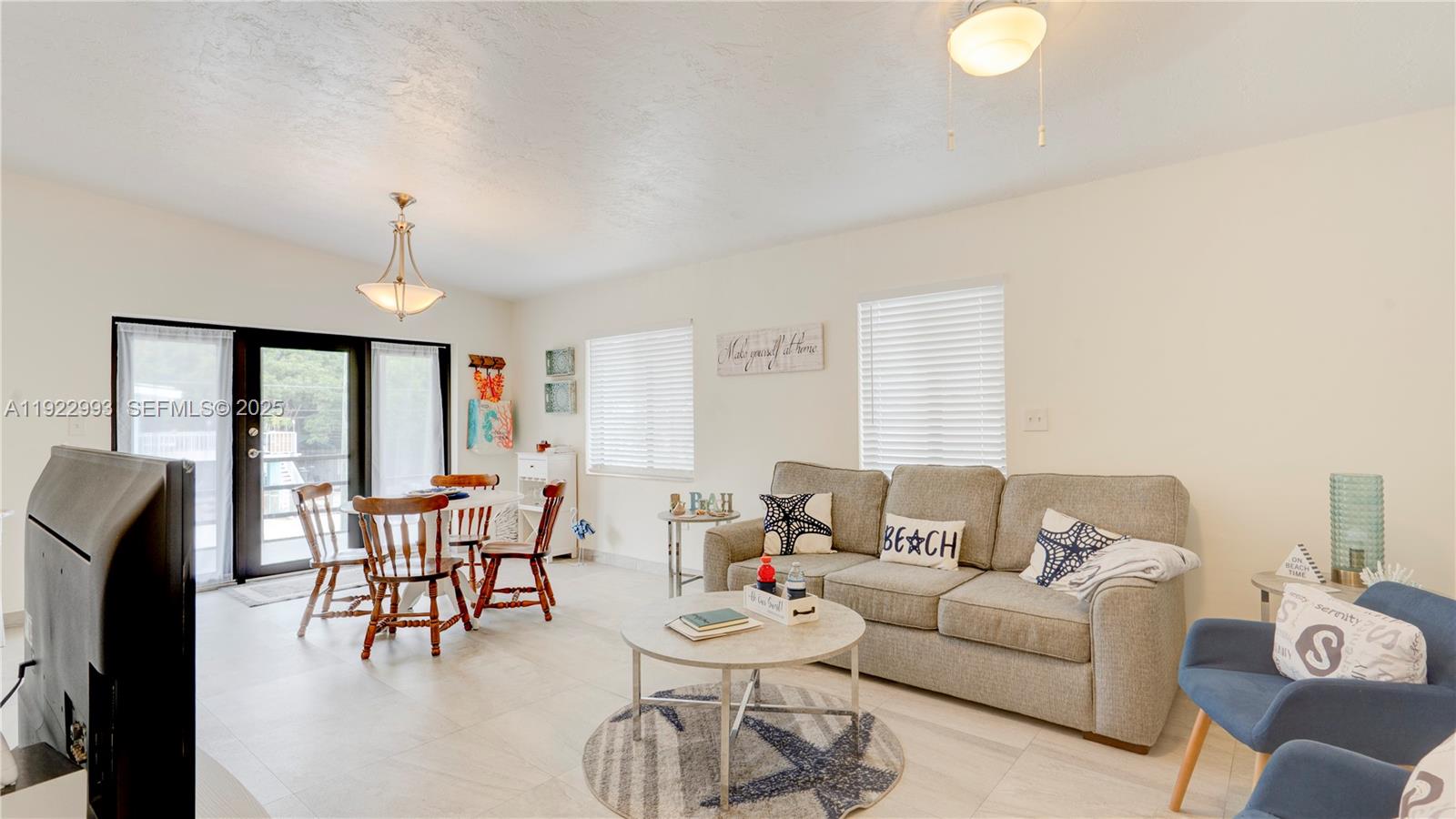 A living and dining area features a gray sofa, round coffee table, and wooden chairs — 137 Pacific Ave, Tavernier FL 33070, TAVERNIER, FL