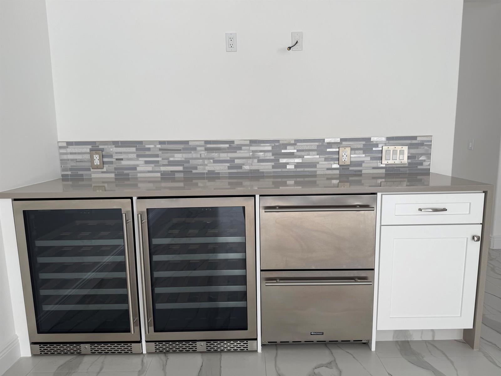 A wet bar features two wine refrigerators, stainless steel drawers, and a white cabinet — 117 Waterford Drive, Jupiter FL 33458, JUPITER, FL