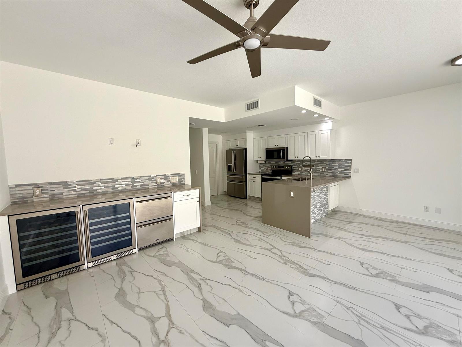 A kitchen features white cabinets, stainless steel appliances, a center island, and marble-patterned tile flooring — 117 Waterford Drive, Jupiter FL 33458, JUPITER, FL