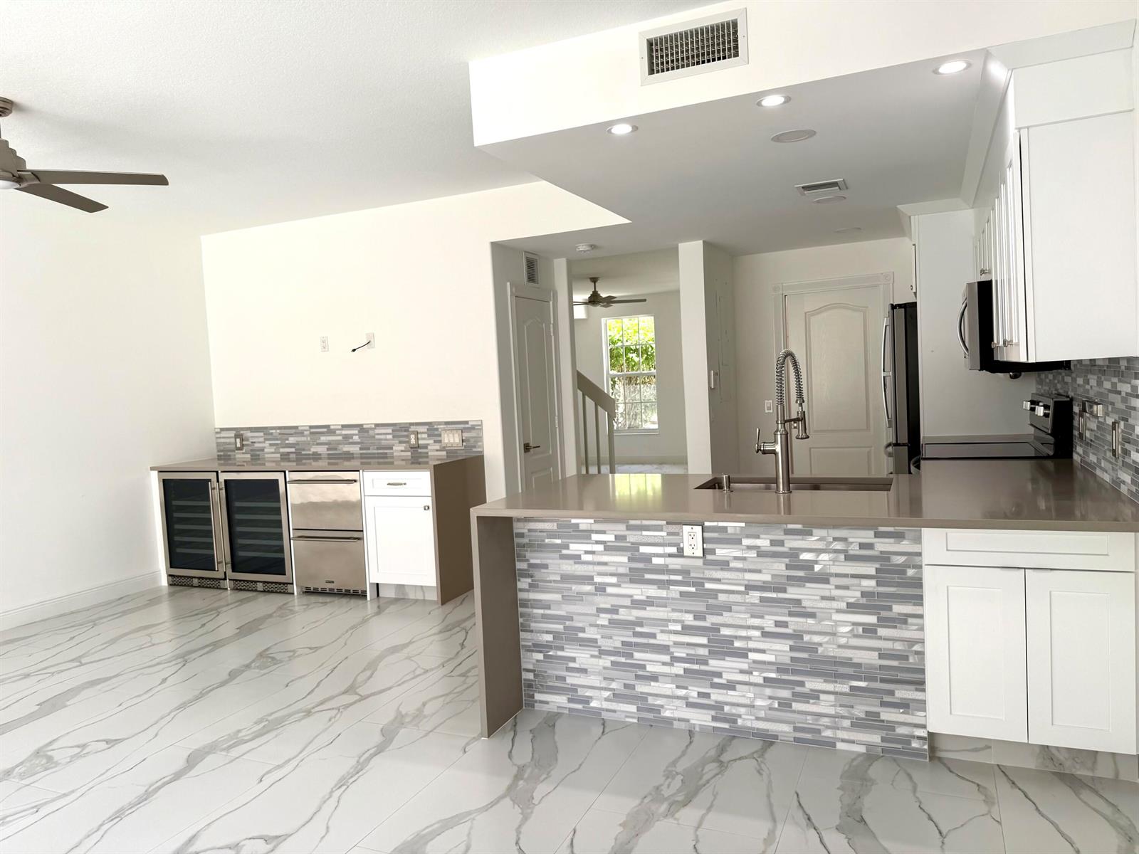 A kitchen with white cabinets, gray countertops, a tiled island, and marble-patterned tile flooring — 117 Waterford Drive, Jupiter FL 33458, JUPITER, FL