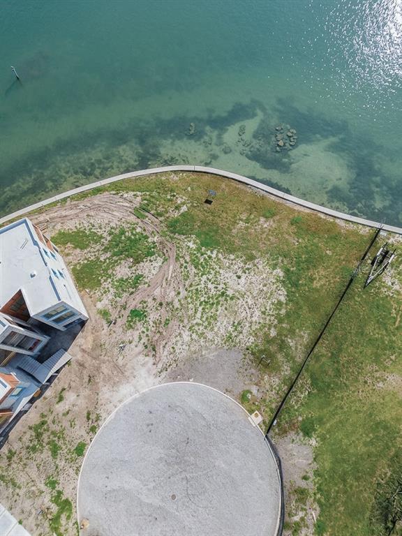 An aerial view shows a waterfront lot with a circular gravel driveway and a building — 5028 W LEONA STREET, TAMPA, FL