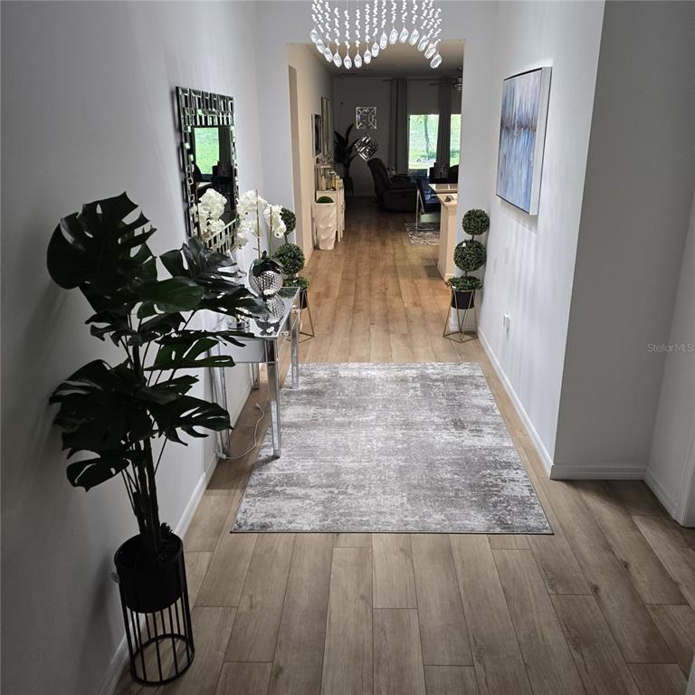 A bright entryway features wood-look flooring, a mirrored console table, and a crystal chandelier — 33259 COUNTRY HOUSE DRIVE, SORRENTO, FL