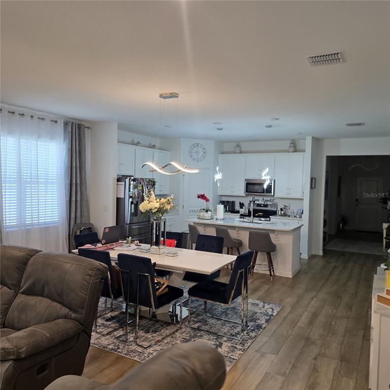 An open-concept kitchen and dining area features white cabinetry, a central island, and modern lighting — 33259 COUNTRY HOUSE DRIVE, SORRENTO, FL