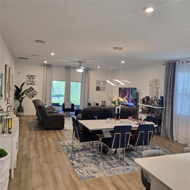 An open-concept living and dining area features wood-look flooring, modern lighting, and neutral walls — 33259 COUNTRY HOUSE DRIVE, SORRENTO, FL